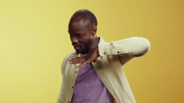 Bir komedi videosu, sakallı bir adamı sarı arka plana karşı abartılı ifadeler ve jestler kullanarak izleyicileri mizahının tadını çıkarmaya davet ederken gösteriyor.