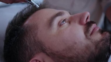 Bir erkek, modern bir kaplıcada yenilenen cilt bakımından zevk alır. Rahatlamak için kaliteli güzellik hizmetleri sunar.