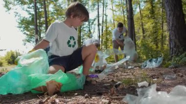 Ormanlık alandaki bir toplum hizmeti projesine katılan bir grup, çevre temizliği ve sorumluluğun geliştirilmesi konularında takım çalışmasının altını çiziyor