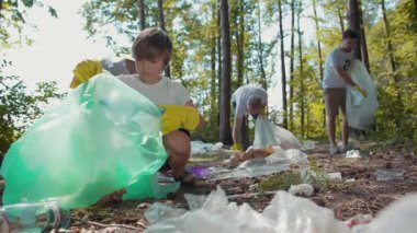 Kendini adamış bir grup insan, çevreyi temiz tutmak için ormanda çöp ve çöp toplamakla meşgul.