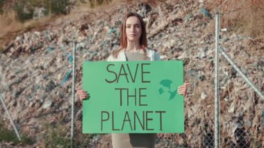 Kendini adamış ve tutkulu bir aktivist, çevresel farkındalığı artırmak için Gezegeni Kurtarın tabelasını tutuyor.