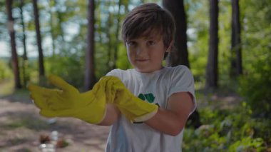 Sakin bir ormanda, sarı lastik eldivenli genç bir çocuk doğayı keşfeder. Çocukluk merakını gösteren bir odun parçasını inceliyor.