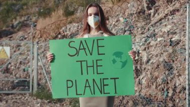Genç bir kadın tutkulu bir şekilde çevrenin korunması ve bilinçlendirilmesi gerektiğini savunan bir tabela tutuyor.