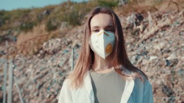 Koruyucu maske takmış genç bir kadın açık havada gururla ve emin bir şekilde duruyor.