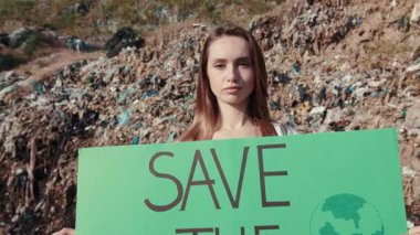 Tutkulu bir aktivist, çevre kirliliği ve çevre koruma konusundaki farkındalığı artırmak için büyük bir işaret taşıyor.