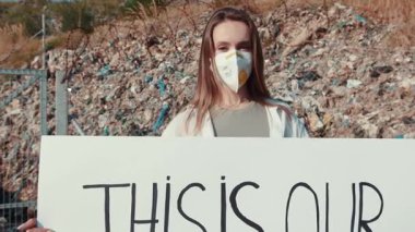 Çevresel adaleti tutkuyla savunan genç bir aktivist, atıkların önünde bir tabela tutuyor.