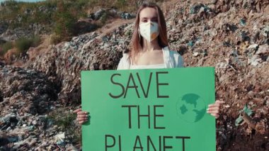 Tutkulu bir çevreci, kirliliğin ortasında gezegenin korunmasını savunan bir tabela tutuyor..