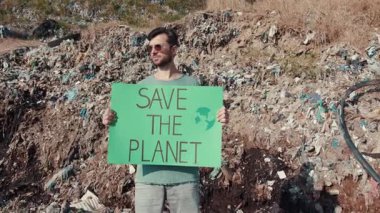Tutkulu bir avukat, acil çevre koruma ve sürdürülebilirlik çağrısında bulunarak atıkların arasında duruyor