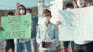 Birleşmiş bir grup aktivist, çevre korumasını desteklemek ve halkı bilinçlendirmek için renkli işaretler taşıyor.