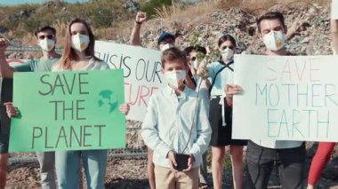 Tutkulu bir grup genç eylemci, ellerinde tabelalar ve maskeler tutarken gezegeni kurtarmak için tutkuyla protesto ediyor.