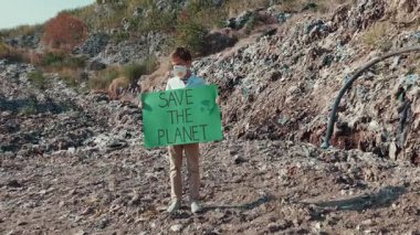Genç bir aktivist, çarpıcı ve kayalık bir arazide çevresel değişimi savunan canlı bir işaret tutuyor.