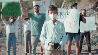 Tutkulu bir genç, sürdürülebilir bir gelecek umudunu simgeleyen yeşil bir fabrikayı gururla elinde tutan bir iklim protestosuna önderlik ediyor.