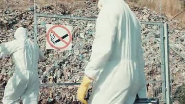 Koruyucu giysili bir tehlikeli madde ekibi önemli bir uyarı işareti ile işaretlenmiş tehlikeli bir bölgeyi araştırıyor.