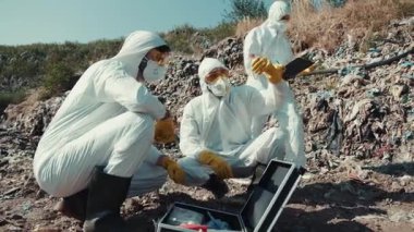 Koruyucu giysiler içindeki eğitimli işçiler tehlikeli bir çevredeki atıkları titizlikle analiz ediyorlar.
