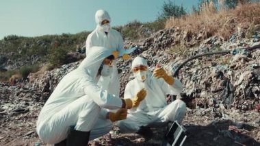 Tehlikeli madde giysisi giymiş özel bir araştırma ekibi bir çevre sahasındaki toprağı titizlikle inceliyor.