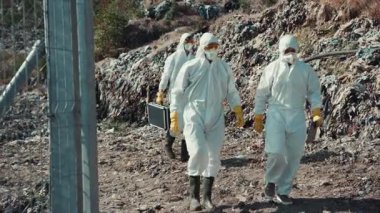 Koruyucu giysiler içindeki kendini işine adamış işçiler tehlikeli bir atık sahasında önemli bir çevre temizliği yapıyorlar.