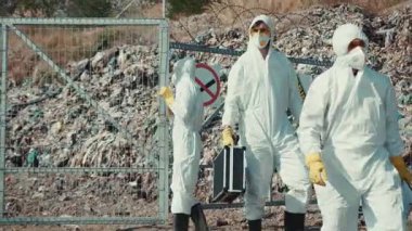 Koruyucu giysiler giymiş iki eğitimli profesyonel tehlikeli atık bölgesini dikkatle araştırıyor.