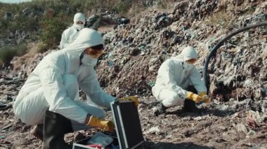 Kirlenmiş bir bölgede, bilim adamları önemli örnekler toplamak için özenle koruyucu giysiler giyiyorlar.
