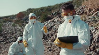 Koruyucu giysi giyen araştırmacılar özellikle detaylı çevre çalışmaları için bir siteyi dikkatle inceliyorlar.