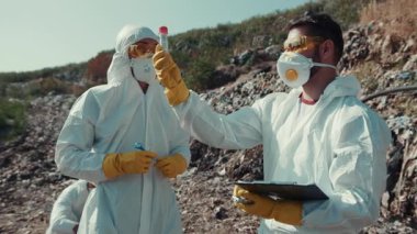 Zorlu bir açık hava ortamında, koruyucu ekipmanlı bilim adamları özenle önemli örnekler topluyor.