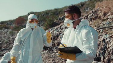 Koruyucu giysiler içinde kendini adamış bir ekip temizlik çalışmaları kapsamında son derece kirli bir bölgeyi dikkatle inceliyor.