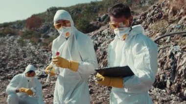 Koruyucu giysiler giymiş bir grup bilim adamı, bir alan düzeninde hayati örnekler topluyor.