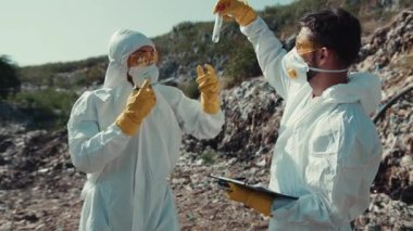 Koruyucu giysiler içindeki iki bilim adamı, güvenlik ve kirlilik kontrolü için bir alanda değerli örnekler topluyorlar.