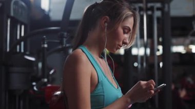 Fit atletik, ciddi, müzik dinleyen genç bir kadın spor salonundaki spor salonundaki spor salonundaki spor salonundaki spor salonundaki spor salonundaki sağlıklı vücut kasları spor kıyafetlerindeki güçlü portreyi kullan.
