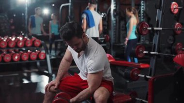 Dambılla egzersiz yapan çekici bir adam spor salonunda akıllı saat, vücut gücü, sağlıklı, kaslı, genç, kardiyo, Kafkas dayanıklılığı portresi.