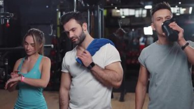 İki erkek ve bir kadın spor salonunda kameraya bakıp gülümsüyor mutlu ışık fitness vücut kuvveti güçlü sağlıklı kas sporcusu genç kol mankeni portresine uyuyor.