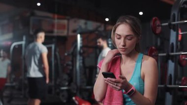 Gülümseyen genç bir kadın spor salonu spor salonu spor salonunda dinlenme spor spor spor spor spor spor spor salonunda sağlıklı vücut kasları spor kıyafetleri güçlü güçlü portre yakın çekim yakın