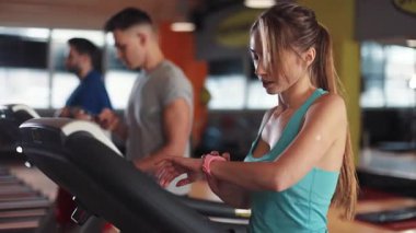 Spor salonundaki koşu bandındaki çekici genç kadın spor spor fitness internet yüz teknolojisi formda spor spor giyim ağı ağları vücut egzersizi sağlıklı mobil akıllı telefon yavaş çekim