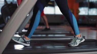 Koşu bandındaki çekici genç kadın spor salonunda güneş ışığı spor spor fitness internet yüz teknolojisi yaşam stili spor spor spor kıyafetleri vücut egzersizi ağır çekimde akıllı telefon kullanıyor.