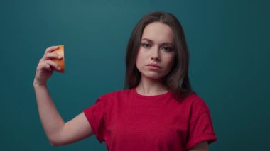 Koyu yeşil arka planda çekici bir kadının yan görüntüsü, kameraya dönüp neşeyle gülümsemesinden ziyade, greyfurtu yüzünün önünde tutar. Sağlıklı yaşam tarzı, vitaminler. Yaklaşın, ağır çekim.