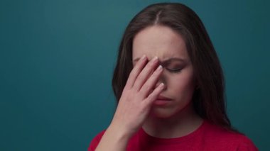 Gözlerini kapayan, alnına dokunan, baş ağrısı çeken, şakaklarına masaj yapan genç bir kadının yakın görüntüsü. Stres, çatışma, acı. Ağır çekim, kadın portresi.