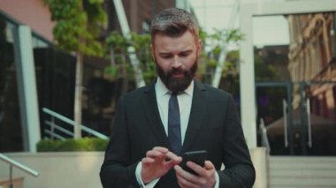 Gülümseyen başarılı iş adamı akıllı telefon kullanıyor. Şehir merkezinin caddesinde yürürken mutlu yüz teknolojisi cep telefonu giysisi şehir modası yakışıklı iş müdürü internet.