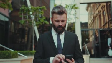 Başarılı iş adamı akıllı telefon kullanır büyük şehir iş caddesinde yürürken mutlu yüz teknolojisi cep telefonu giysisi şehir modası yakışıklı iş müdürü internet