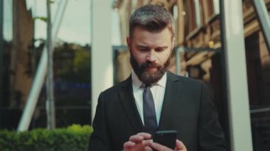 Başarılı bir iş adamı akıllı telefon kullanır ve büyük şehir ticaret caddesine gider gülümseyerek güler yüzlü cep telefonu giysisi şehir modası yakışıklı iş müdürü internet