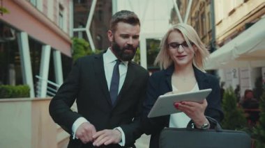 Gülümseyen iş adamı ve kadın birlikte tablet bilgisayar kullanın açık havada sohbet yakışıklı internet teknolojisi çift şirket yönetim şehir şehir şehir şehir şehir genç takım çalışması