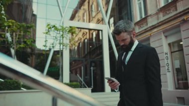 Ciddi anlamda başarılı bir iş adamı akıllı telefon kullanır. Şehir merkezindeki büyük işletme caddesine git. Teknoloji cep telefonu giysisi.