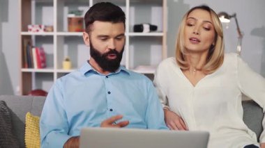 Bir çift, bir dizüstü bilgisayar üzerinde işbirliği içinde çalışırken, takım çalışması yaparken, anlayışlı bir sohbeti paylaşıyor.