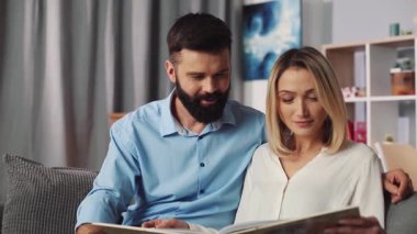 Sevgi dolu bir çift, evlerinde sevgi dolu bir fotoğraf albümüne bakarken samimi ve samimi bir anı paylaşır.