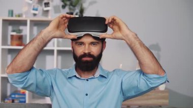 Bir adam sıcak bir oturma odasında kulaklık takarak sanal gerçekliğe dalmaya hazırlanıyor.