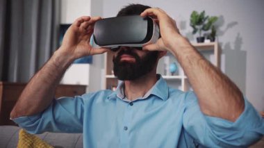 Bir adam oturma odasında sanal gerçekliği keşfeder, çeşitli daldırıcı deneyimlerden zevk alır.
