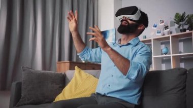 Bir adam oturma odasında dinlenirken sanal gerçeklik oyunu deneyiminin tadını çıkarıyor.