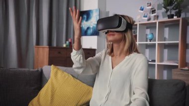 Bir kadın evde rahatça dinlenirken sanal gerçeklik teknolojisinin heyecan verici dünyasıyla meşgul oluyor.