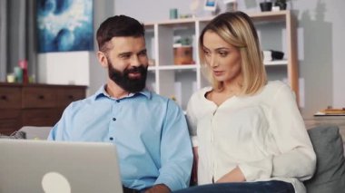 Bir çift, takım çalışmasını ve iletişimi rahat ve modern bir ortamda gösteren bir dizüstü bilgisayar kullanıyor.