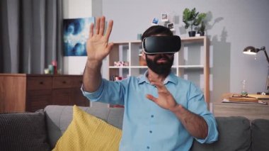 VR kulaklık takan bir adam, oturma odasındaki sanal elementlerle etkileşime girer.