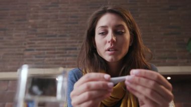 Baş ağrısı olan üzgün bir portre. Sıcaklık ölçer. Telefon kullan.