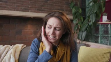 Genç bir kadının diş ağrısı var. Evdeki virüs hastalığında koltukta oturuyor. Soğuk hava semptomları.